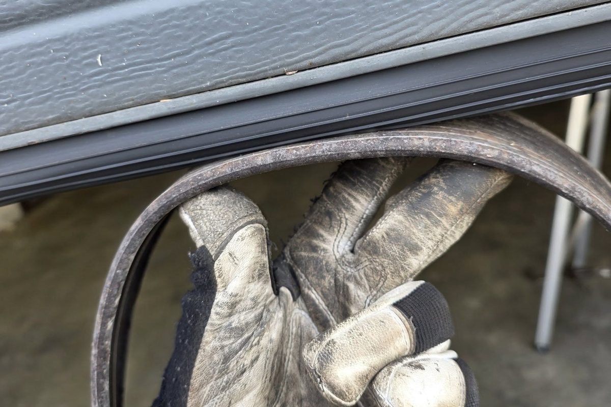 Worn garage door bottom seal held up next to the door during replacement