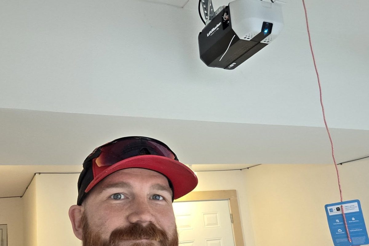 A newly installed LiftMaster belt-drive opener on a garage ceiling, with Zach Wallace below