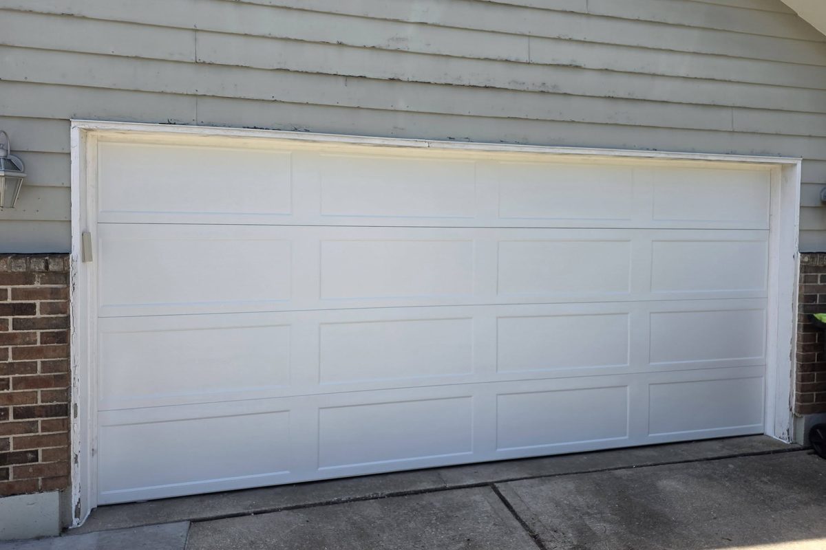 Replacement garage door installed on a brick and siding home
