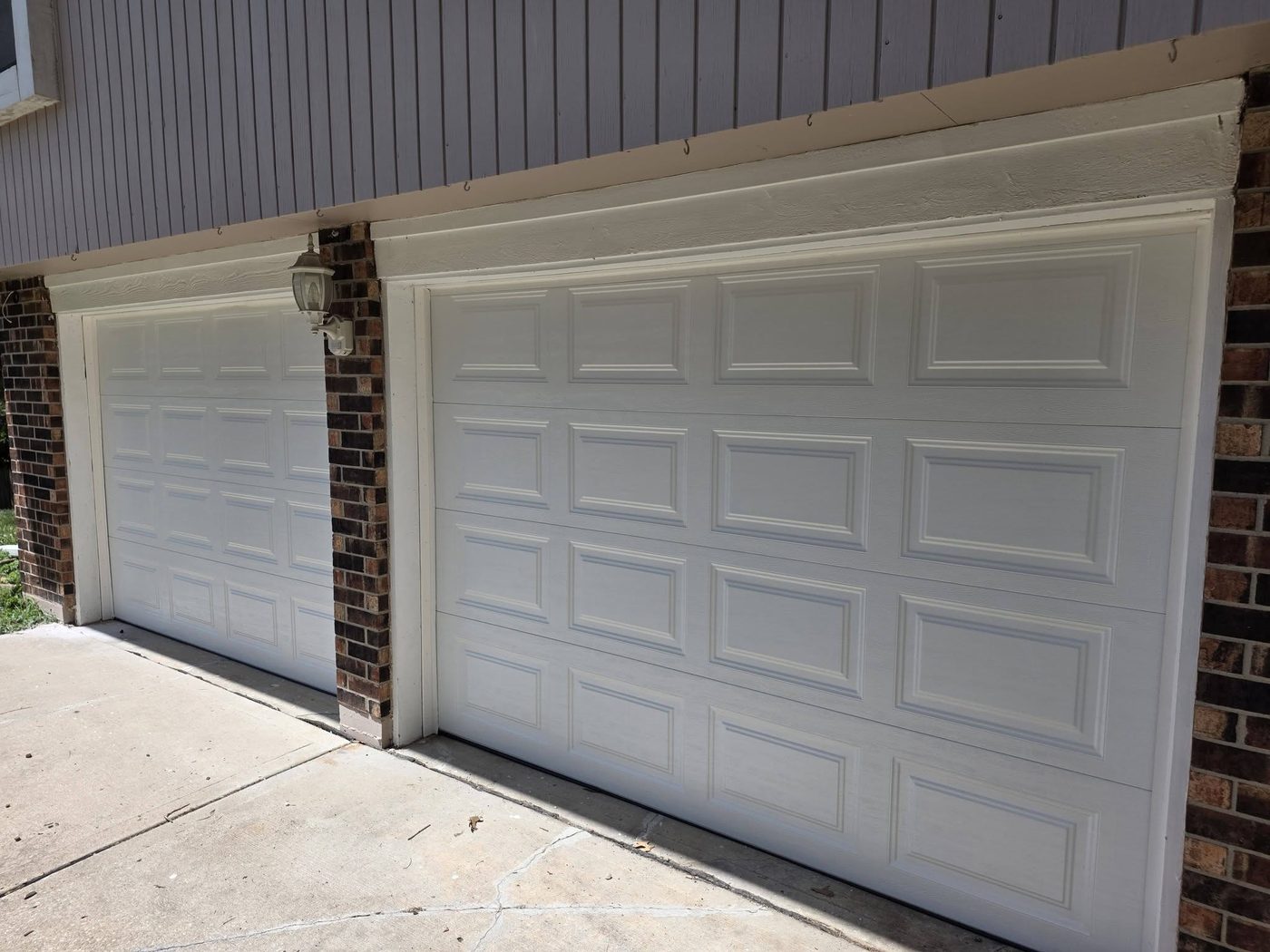 New white raised-panel garage doors after replacement