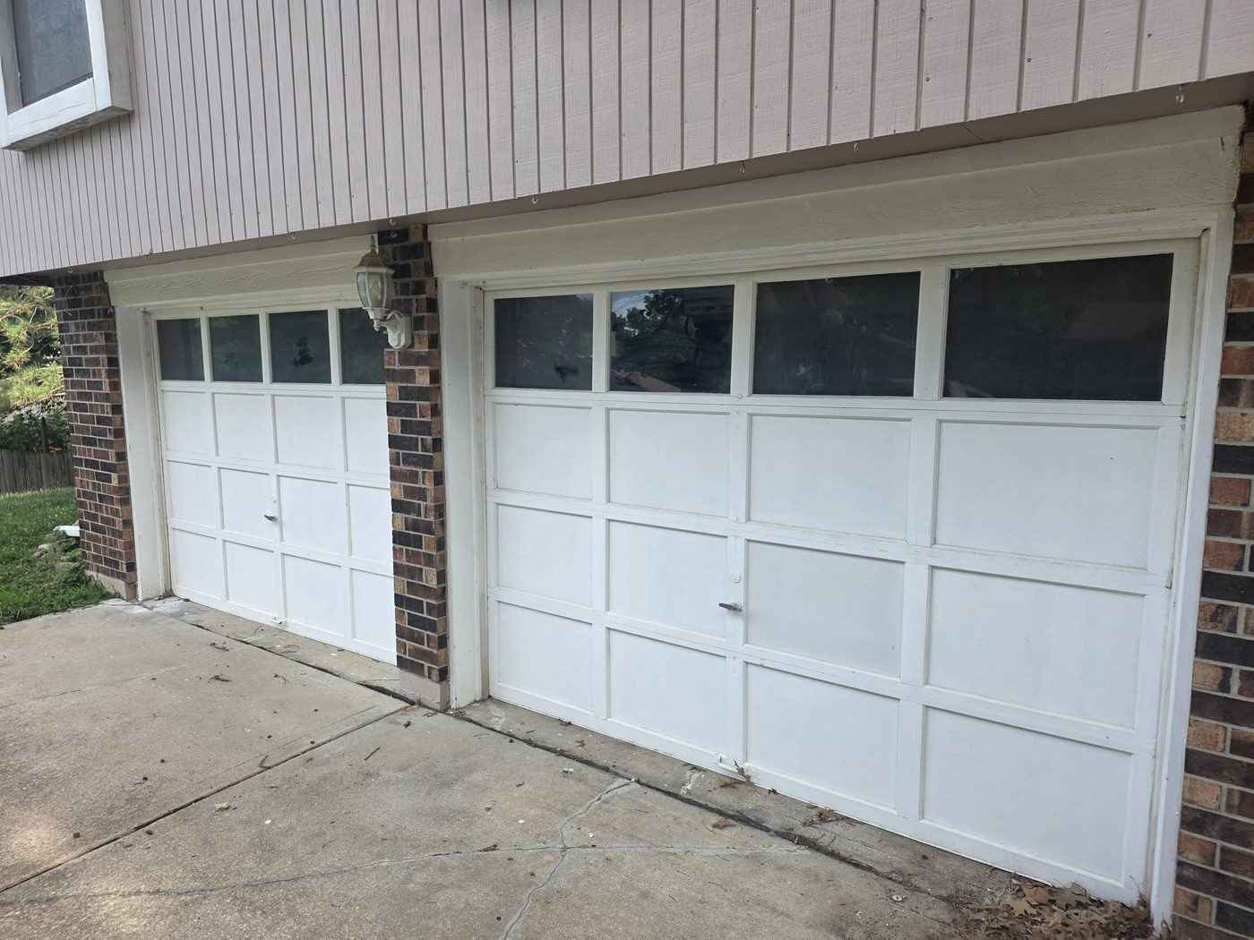 Worn two-car garage door with windows before replacement