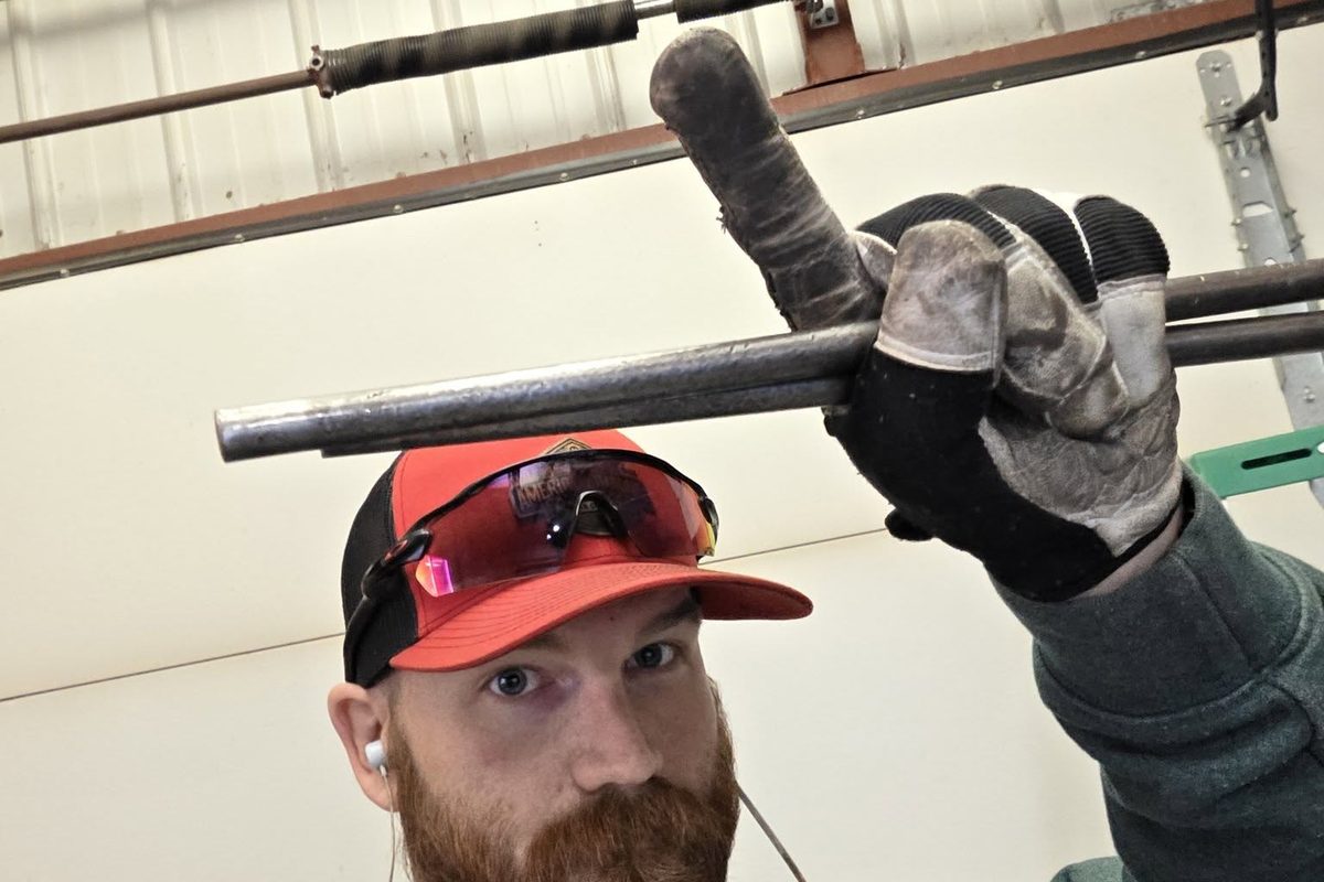 Zach Wallace holding the winding bars under a torsion spring during a spring replacement